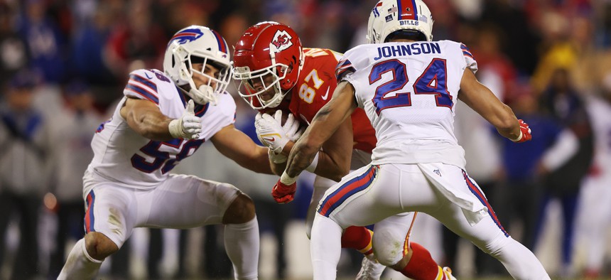 Travis Kelce of the Kansas City Chiefs runs between two defenders during a playoff game Jan. 23 against the Buffalo Bills.