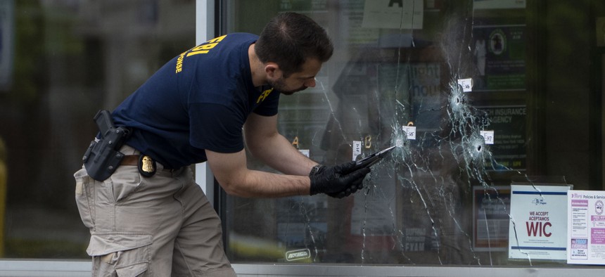 An FBI investigator collects evidence from bullet holes in the window of Tops Friendly Market, the scene of the fatal shooting of 10 people in Buffalo, New York.