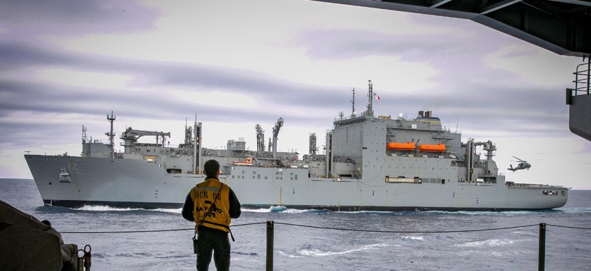 The Military Sealift Command dry cargo ship USNS William Mclean sails alongside the aircraft carrier USS George H.W. Bush while unloading ammunition in April 2022.