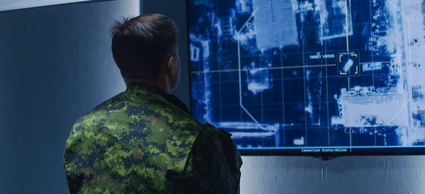 In this photo illustration, a military officer tracks a vehicle on a wall monitor.