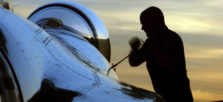 An airman works on the canopy of a F-16 fighter jet.