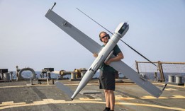 Michael Uridil places a Flexrotor long-range robotic aircraft on the flight deck of the guided missile destroyer USS McFaul (DDG 74) during flight operations, July 23, 2023. 
