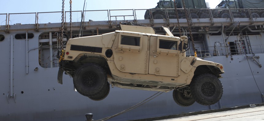 A crane loads a Marine Corps  Humvee onto the flight deck of the USS Carter Hall at the Morehead City, North Carolina.