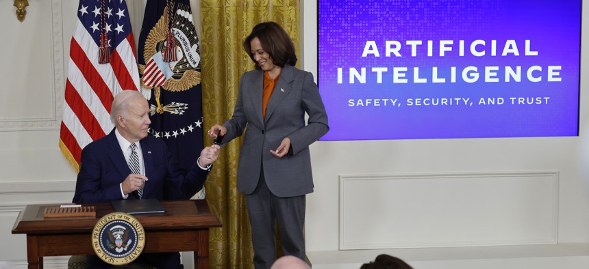 President Joe Biden hands Vice President Kamala Harris the pen he used to sign a new executive order on artificial intelligence in the East Room of the White House on October 30, 2023.