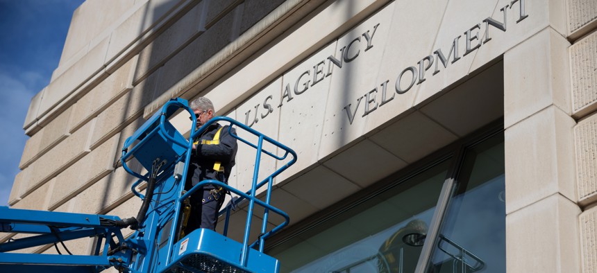 A worker removes the U.S. Agency for International Development sign on their headquarters on Feb. 7, 2025, in Washington, D.C. A federal judge said Friday he would issue a temporary restraining order before midnight preventing the agency from placing employees on administrative leave.
