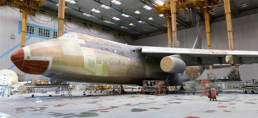 A military cargo jet undergoing maintenance and painting.