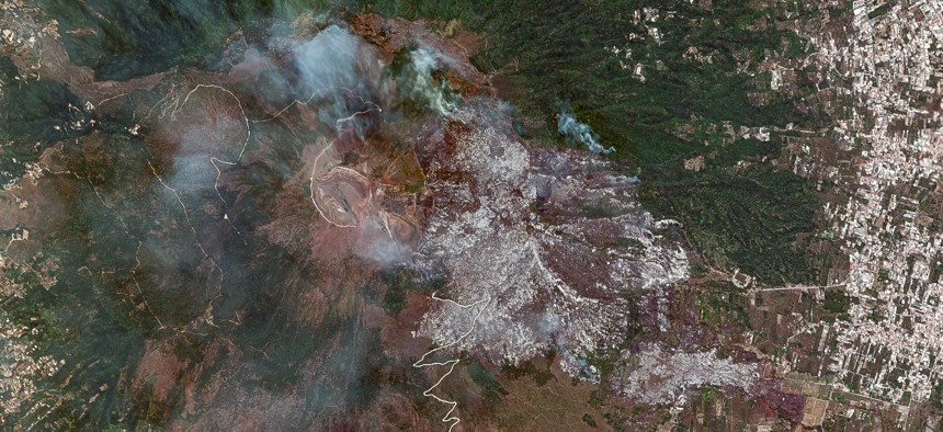 Maxar satellite imagery shows active smoke plumes and extensive burn scars covering large areas of forested terrain within and around Vesuvius National Park.