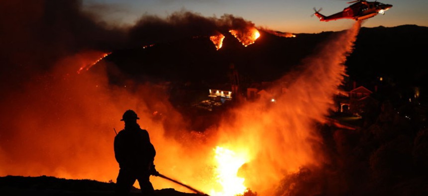 A helicopter drops water as the Palisades Fire grows in California last January.