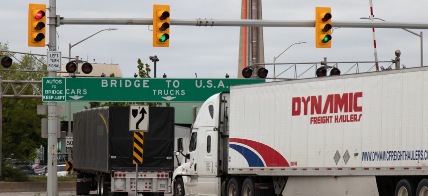 Tractor-trailers pass under a "Bridge To USA" sign at the entrance to the Ambassador Bridge at the US-Canada border crossing.