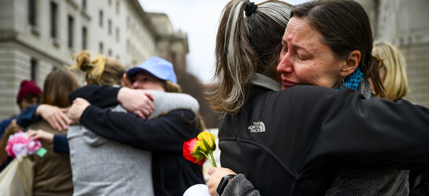 U.S. Agency for International Development staffers and supporters embrace outside of the agency's former offices on Feb. 27, 2025, in Washington, D.C. The documentary "Heist" features video of USAID employees leaving the headquarters after collecting their belongings.